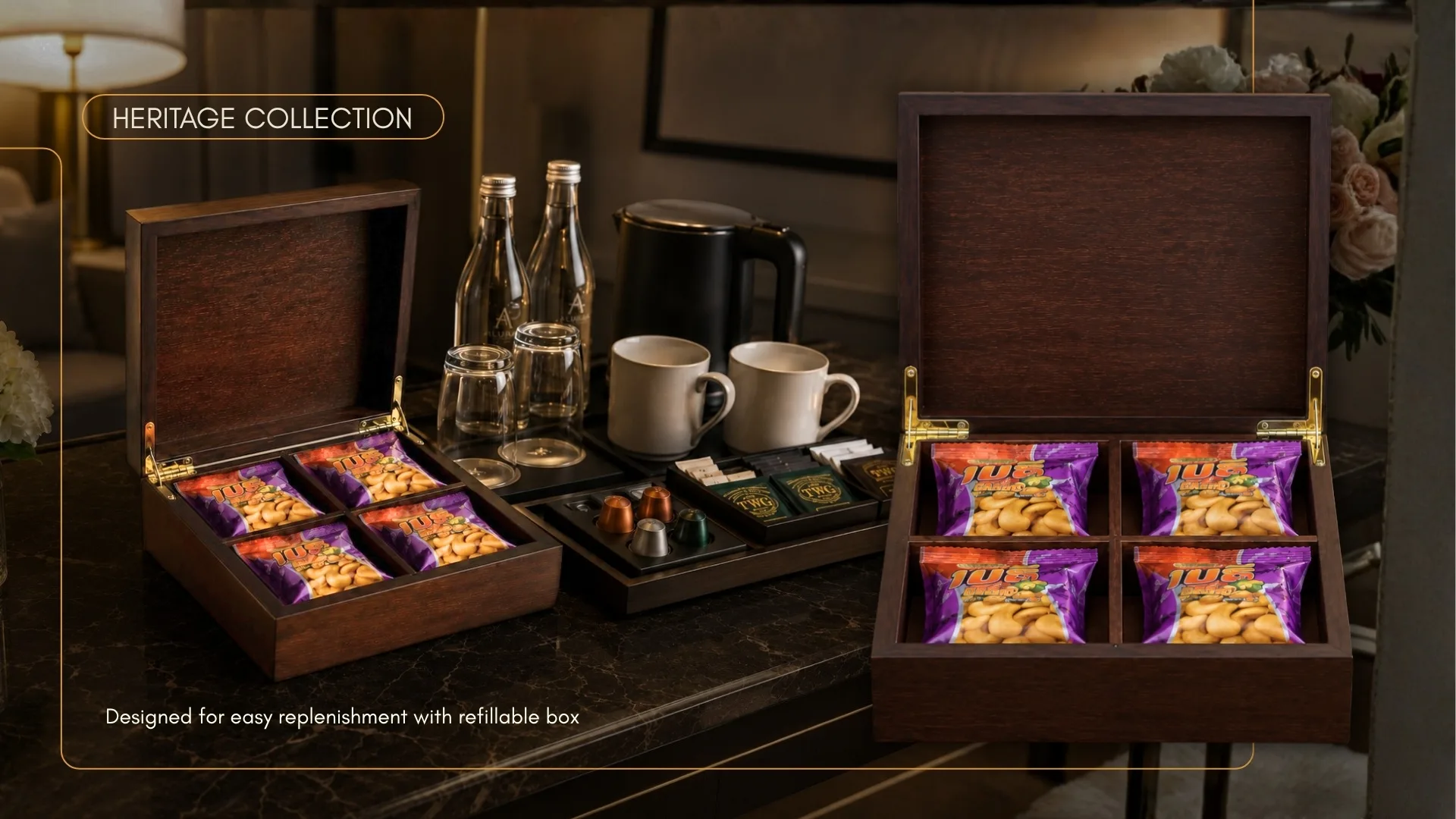 Two open wooden minibar chests of cashew sachets on a hotel console beside a kettle and beverage tray